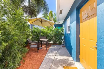 a blue and yellow house with a table and an umbrella at Lovely 2 BR condo in Sailboat Bend in Fort Lauderdale