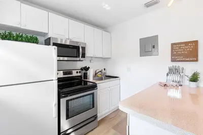 a white kitchen with a stove and a refrigerator at Musicians Lounge - 2 BR with parking asssigned in Fort Lauderdale