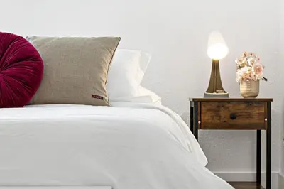 a bed with a red pillow and a table with a lamp at Stylish 2 BR Condo - Free Parking on Premises in Fort Lauderdale