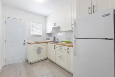 a kitchen with white cabinets and a white refrigerator at Victoria Park Unique Studio close to Las Olas Blvd in Fort Lauderdale
