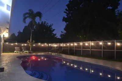 a swimming pool at night with lights on a fence at Spacious 4 bedrooms, 2 bathroom house with pool in Miramar