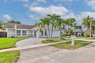 a house with palm trees in the driveway at Spacious 4 bedrooms, 2 bathroom house with pool in Miramar