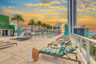 a balcony of a building with a pool and palm trees at Bayview Luxury: 3BR Pools Oceanfront Amenities in Hollywood