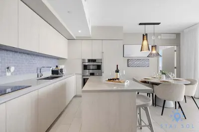 a kitchen with white cabinets and a table with a bottle of wine at Bayview Luxury: 3BR Pools Oceanfront Amenities in Hollywood