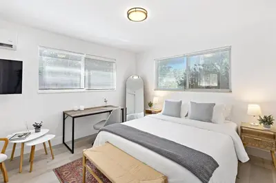 a bedroom with a large white bed and a desk at Lovely Studio with Great Location + Free Parking in Fort Lauderdale