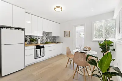 a kitchen with white cabinets and a table with chairs at Lovely Studio with Great Location + Free Parking in Fort Lauderdale