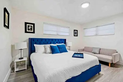 a bedroom with a large bed and a couch at Villa Oasis 3 Miles to Hard Rock Stadium & Casino, Guitar Hotel Nearby, Pool, Game Room, Sleeps 12, 15 Min to Beach in Pembroke Pines
