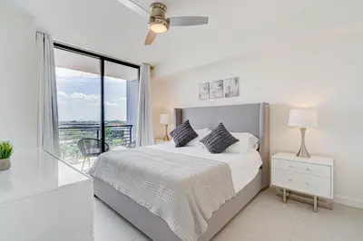 a white bedroom with a bed and a balcony at 805MM DOWNTOWN DORAL CONDO 2 BEDROOMS & 2 BATHROOMS in Miami