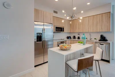a kitchen with a refrigerator and a counter with chairs at 3900-717AS DESIGN DISTRICT, CONDO 2 BEDROOMS & 2 BATHROOMS & BAY in Miami