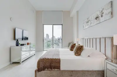 a white bedroom with a bed and a large window at 3900-504MQ DESIGN DISTRICT, CONDO 1 BEDROOM & 1 BATHROOM in Miami