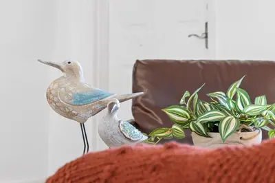 two statues of birds on a couch next to a plant at The Perfect Escape @Lake Ridge in Fort Lauderdale