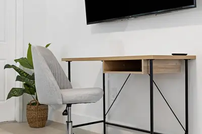 a desk with a chair and a tv on a wall at Charming cozy studio @ Lake Ridge in Fort Lauderdale