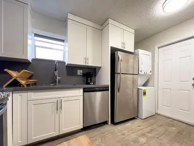 a kitchen with white cabinets and a stainless steel refrigerator at Hidden Garden: A Serene Miami Escape in Cutler Bay