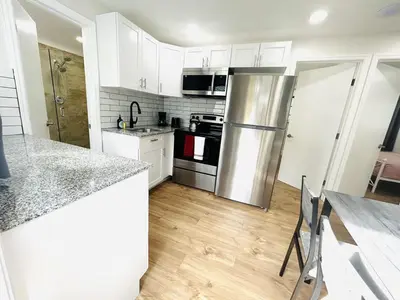 a kitchen with white cabinets and a stainless steel refrigerator at Progresso Apartments & Homes by Lowkl in Fort Lauderdale