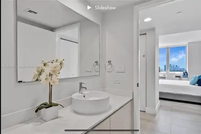a white bathroom with a sink and a bedroom at Apartment 3B/3B Bay View in Hallandale Beach