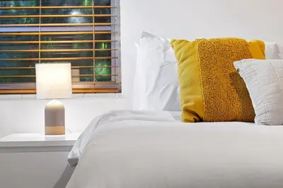 a white bed with a yellow pillow and a window at Welcoming Airbnb Walkig distance to Las Olas Blvd in Fort Lauderdale