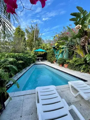 a swimming pool with two lawn chairs and an umbrella at Beautiful Apt in Victoria Park (Las Olas Blvd) in Fort Lauderdale