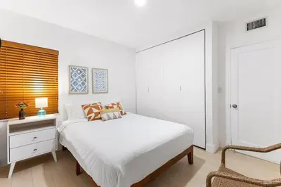 a white bedroom with a bed and a chair at Bright and Stylish Apt in Las Olas Blvd Victoria Park in Fort Lauderdale