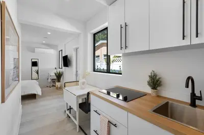 a kitchen with white cabinets and a sink and a desk at Mango House en Dania Beach in Dania Beach