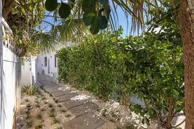 a stone pathway next to a white building with trees at Mango House en Dania Beach in Dania Beach