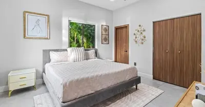 a bedroom with a bed and a wooden cabinet at Waterfront Mansion The GlamHomes in North Miami Beach