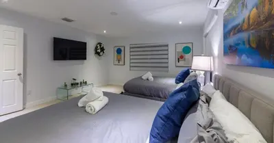 a bedroom with two beds and a tv on the wall at New Oasis Waterfront & Sand Terrace THG in Miami