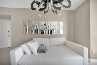 a white couch in a living room with a chandelier at Water & Pool Views, One bedroom W hotel building in Miami
