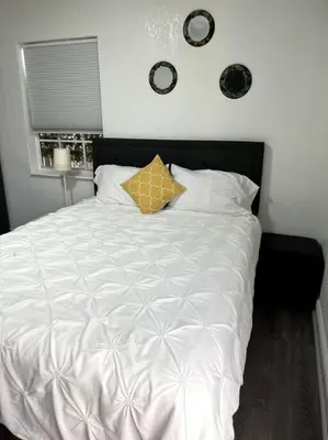 a bedroom with a white bed with a yellow pillow at Nice and Cozy guest house in Miami