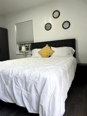 a bedroom with a white bed with two clocks on the wall at Nice and Cozy guest house in Miami