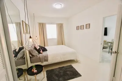 a white bedroom with a bed and a mirror at BEAUTIFUL APARTMENT FOOTSTEPS FROM THE BEACH in Miami Beach