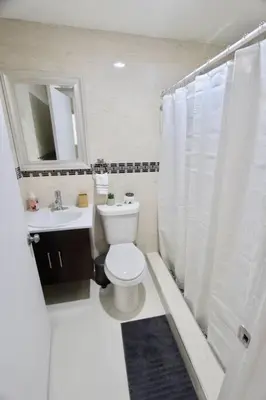 a white bathroom with a toilet and a sink at BEAUTIFUL APARTMENT FOOTSTEPS FROM THE BEACH in Miami Beach