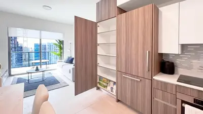a kitchen with wooden cabinets and a living room at New 1/1 Apartment in Smart Brickell with Parking in Miami