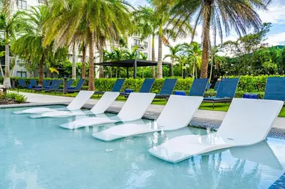 a row of white chairs and chairs in a pool at Modern 1 Bed in Downtown Doral With Free Parking in Hialeah Gardens