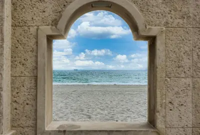 anorthole view of the beach through a stone window at Beach Paradise, Family - Friendly, Free Parking in Hollywood