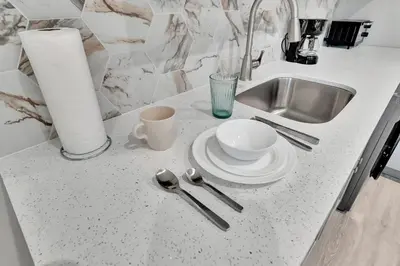 a kitchen counter with a sink and a plate and spoon at 2 Condo Combo Walk to Beach Off Las Olas 2AB in Fort Lauderdale
