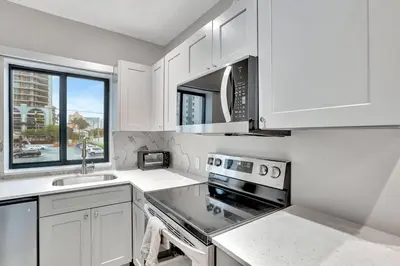a kitchen with white cabinets and a stove top oven at 2 Condo Combo - Walk to Beach Off Las Olas 1AB in Fort Lauderdale