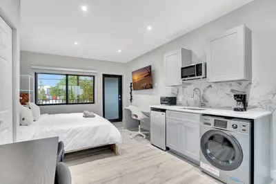 a bedroom with a bed and a kitchen with a washing machine at 2 Condo Combo - Walk to Beach Off Las Olas 1AB in Fort Lauderdale