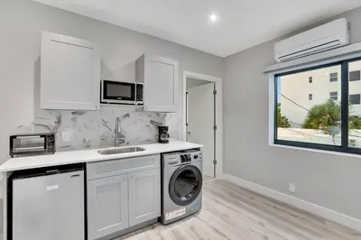 a white kitchen with a washing machine and a window at 2 Condo Combo - Walk to Beach Off Las Olas 1AB in Fort Lauderdale