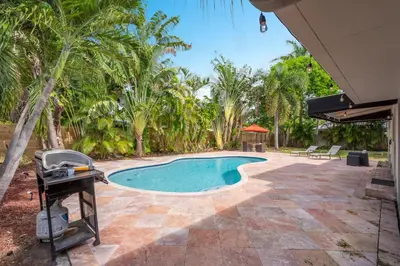 a swimming pool with a grill and palm trees at Wills off Wilton Drive 2 bed and 1 bath plus Den with Heated Pool in Fort Lauderdale