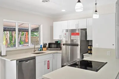 a kitchen with white cabinets and stainless steel appliances at Wills off Wilton Drive 2 bed and 1 bath plus Den with Heated Pool in Fort Lauderdale