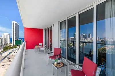 a balcony with red chairs and a view of the city at Condo Retreat with Stunning Views and Amazing Pools in Hallandale Beach