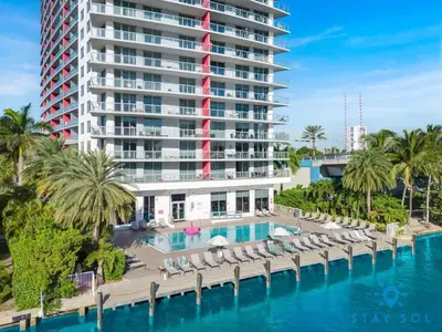 a resort with a pool and chairs and a large building at Condo Retreat with Stunning Views and Amazing Pools in Hallandale Beach