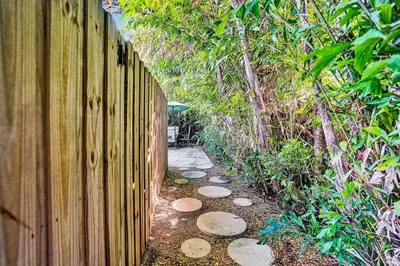 a wooden fence with a path next to a garden at Heated pool, parking, 5 min walk to food and fun! in Fort Lauderdale