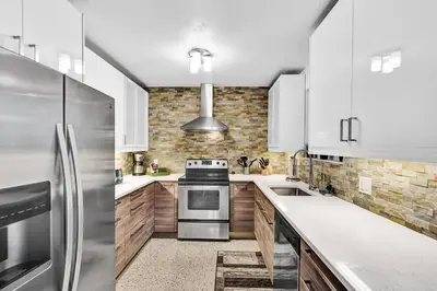 a kitchen with white cabinets and a stainless steel refrigerator at Heated pool, parking, 5 min walk to food and fun! in Fort Lauderdale