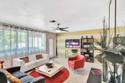 a living room with a white couch and a red chair at Heated pool, parking, 5 min walk to food and fun! in Fort Lauderdale