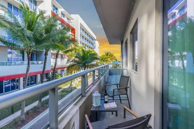 a balcony with chairs and a table and palm trees at Amazing Pool - Hot Tub - Gym - Near Beach in Hollywood