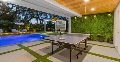 a ping pong table in a backyard with a pool at Entertaining Villa Fun Games Mini Golf Grill in Miami