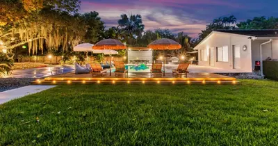 a backyard with a lawn with chairs and umbrellas at New Hidden Gem in Miami