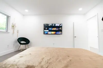 a bedroom with a bed and a black chair at Villa w/a Huge Terrace & Grill Mini Golf Pool in Miami