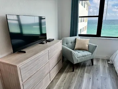 a bedroom with a tv and a chair and a couch at Directly on the Beach with Pool & Ocean View in Miami Beach